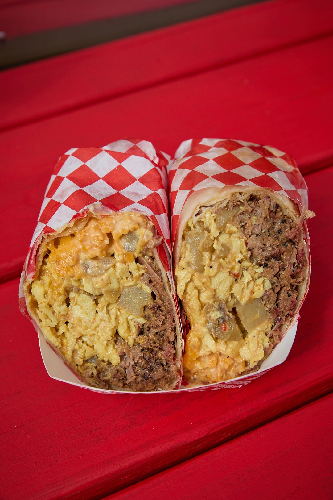 A Two Goose breakfast burrito cut in half, layered with smoked brisket, scrambled egg, potato and cheese