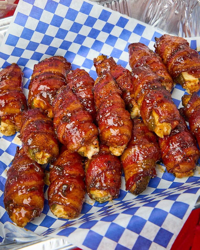 Bacon-wrapped quail poppers, glazed and stacked on checkered paper
